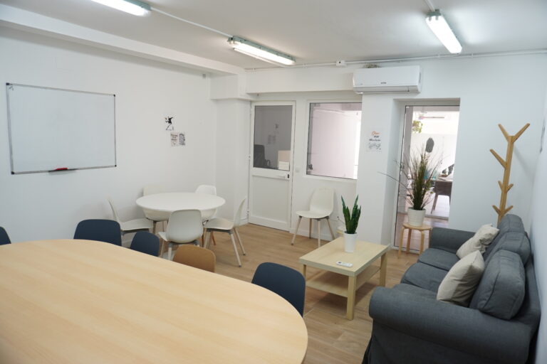 Salas de reuniones por horas Málaga, moderna en Grow Working Málaga con sofá gris, mesas blancas y luz natural